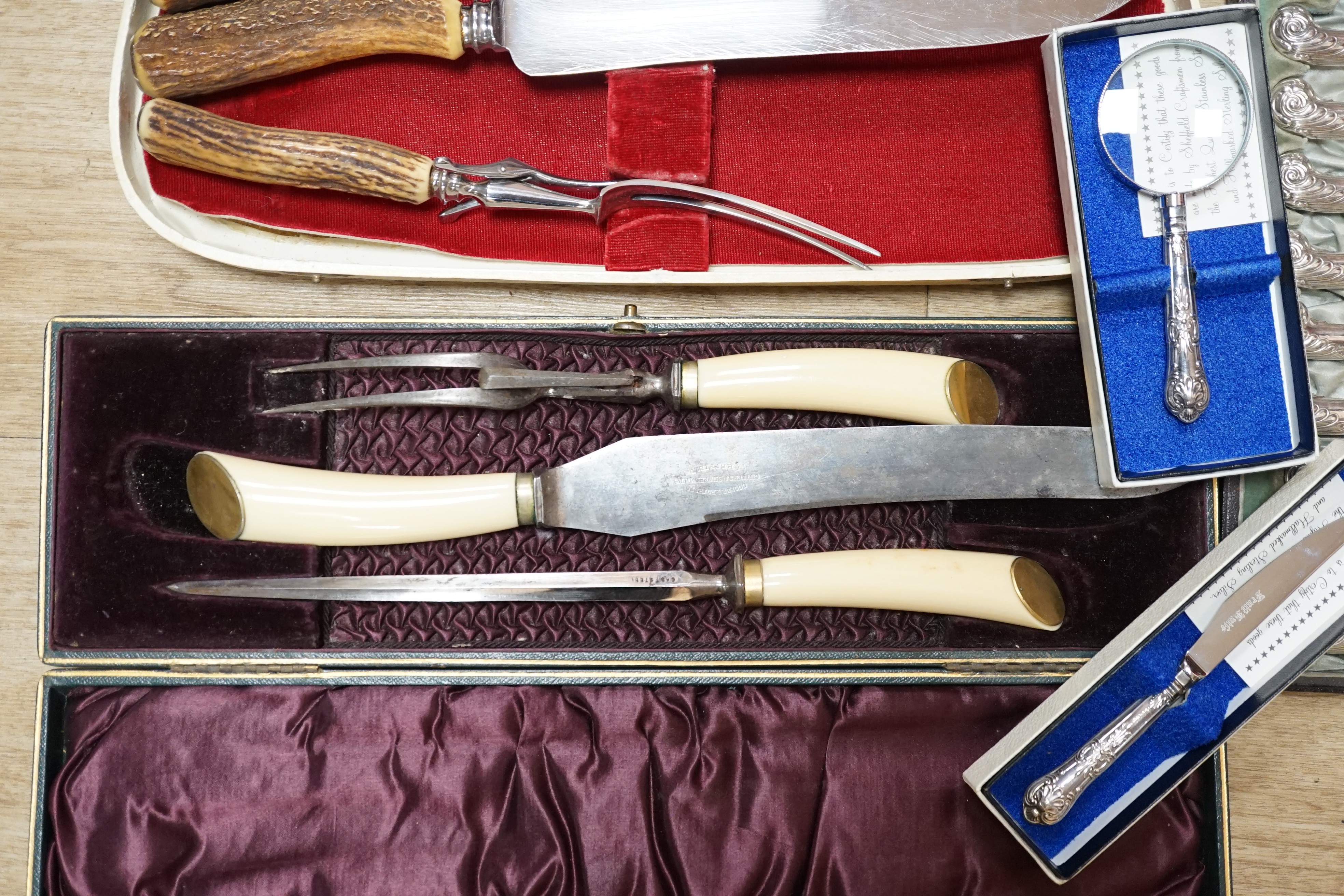 Two cased plated carving sets, a cased set of silver handled cake knives, a modern silver handled magnifying glass and cake slice.